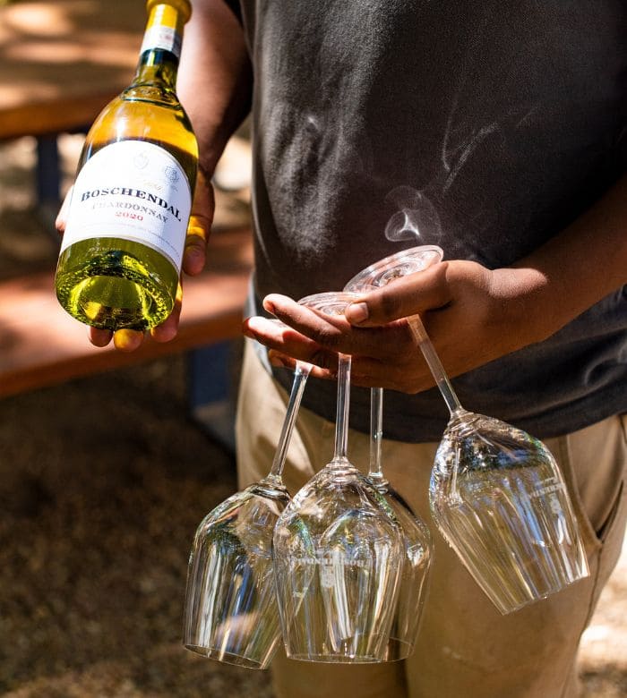 man holding wine glasses and bottle of wine