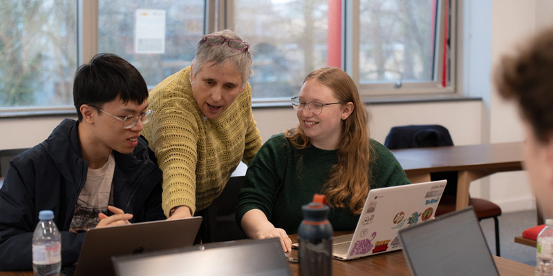 Two students in a disussion with an academic about their work.