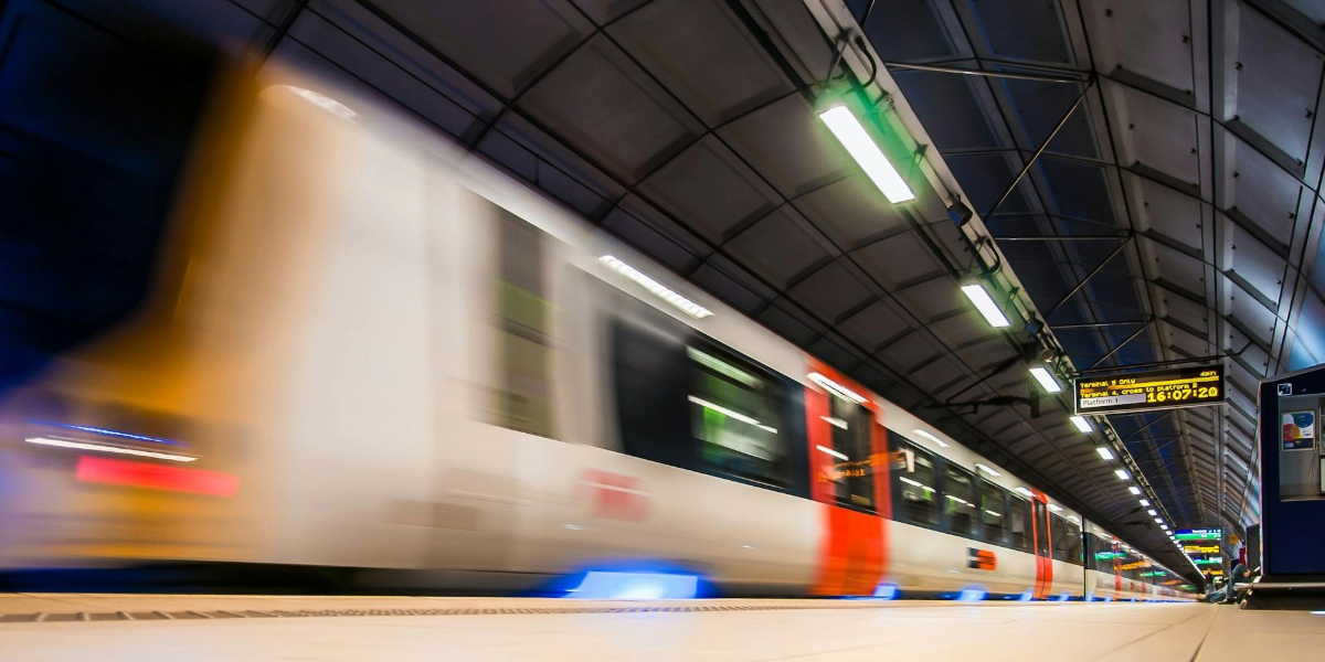 A train speeds through an station in a tunnel with bright platform signage