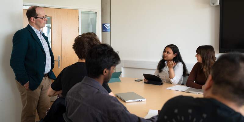 students in a seminar speaking to a lecturer in a meeting room in the department of computer science
