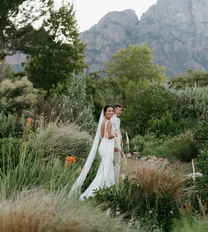 bride and groom in a garden with mountains as the backdrop
