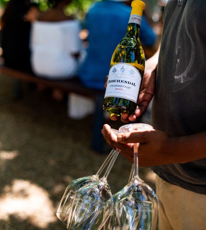 man holding wine glasses and a bottle of wine